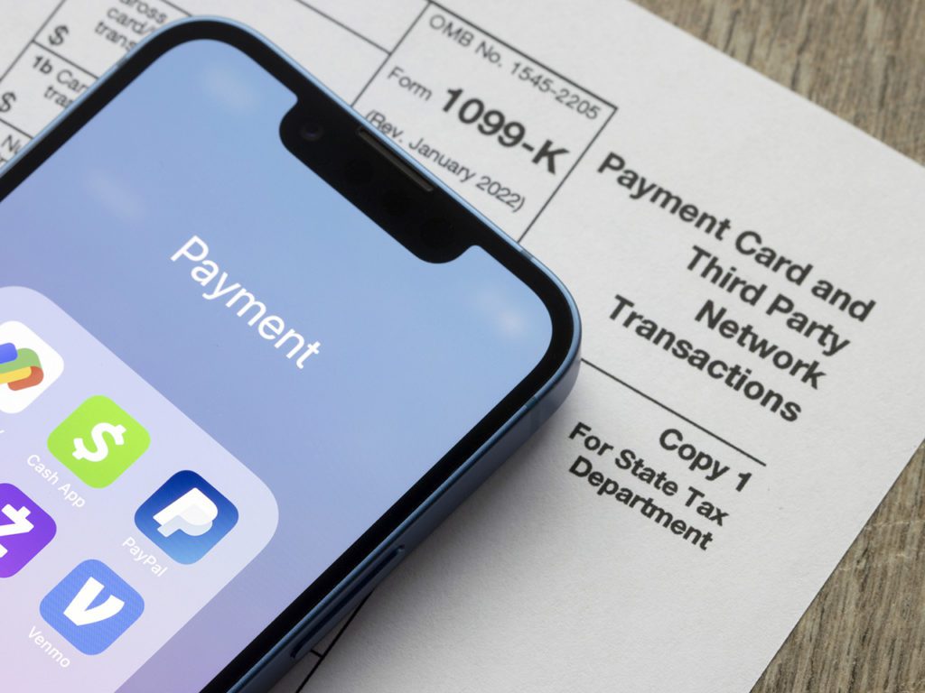 Portland, OR, USA - Jan 5, 2022: Payment apps like PayPal and Venmo are seen on an iPhone on top of Form 1099-k. Third-party payment apps now have to report transactions more than USD600 to the IRS.